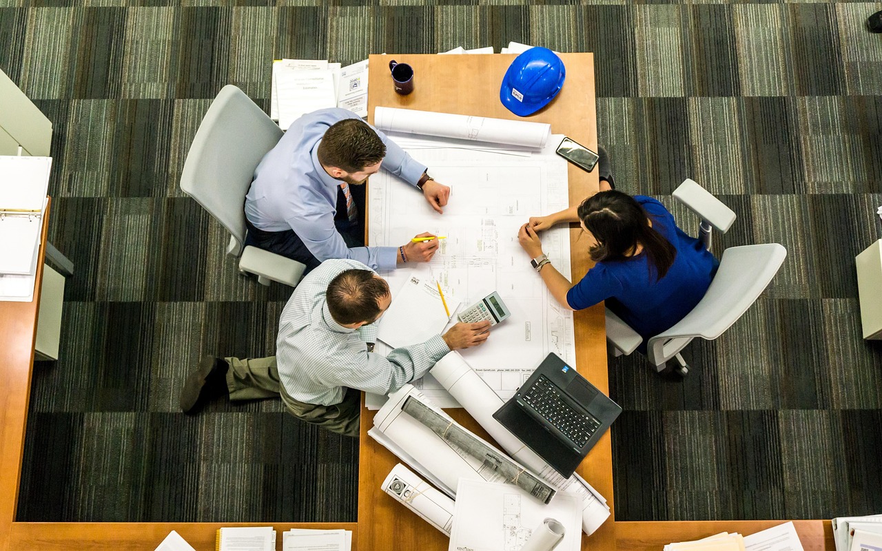 Construction plans, a hard hat and a calculator on an office table